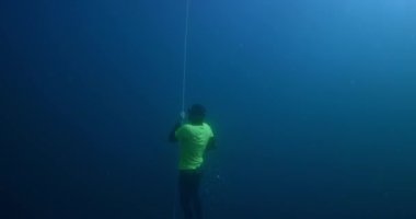 Erkek serbest dalgıç açık denizde serbest dalış eğitimi sırasında halat boyunca yükselir.