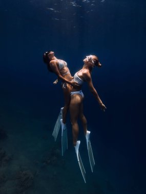 Kız arkadaşlar derin okyanusta sarılıp süzülüyorlar. Suyun altında birkaç bayanla serbest dalış.