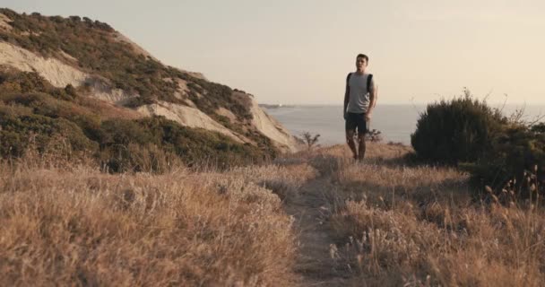 Пішохідний Чоловік Футболці Шортах Рюкзаком Йде Узбережжі Теплим Сонячним Світлом — стокове відео