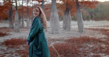 Parkta yürüyen ve kameraya bakan çekici bir kadın. Sonbahar parkındaki insanların portresi. Etkin yaşam biçimi.