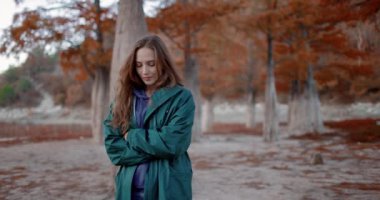 Parkta yürüyen ve kameraya bakan çekici bir kadın. Sonbahar parkındaki insanların portresi. Etkin yaşam biçimi.