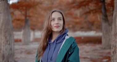 Parkta yürüyen ve kameraya bakan çekici bir kadın. Sonbahar parkındaki insanların portresi. Etkin yaşam biçimi.