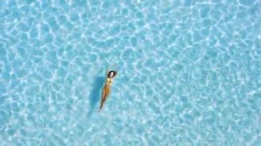 Kadın şeffaf mavi okyanusta dinleniyor ve yüzüyor. Hava görünümü, üst görünüm.