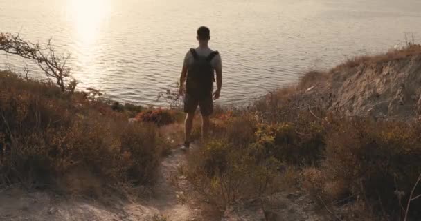 Turysta Shircie Spodenkach Plecakiem Spacerujący Wybrzeżu Ciepłym Światłem Zachodzącego Słońca — Wideo stockowe