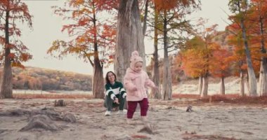Mutlu anne ve güzel kızı sonbahar parkında yürüyüp oynuyorlar. Küçük kız ve anne ormanda yürür.