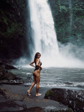 Bali 'de şelalenin yanında bikinili güzel bir kadın poz veriyor..
