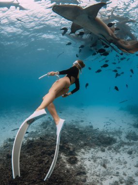 Zayıf bir kadın Maldivler 'de hemşire köpekbalıklarıyla berrak bir tropikal suya dalıyor.