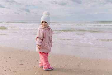 Okyanus kıyısında yürüyen küçük bir kız çocuğu. Kaliforniya kış tatili konsepti.