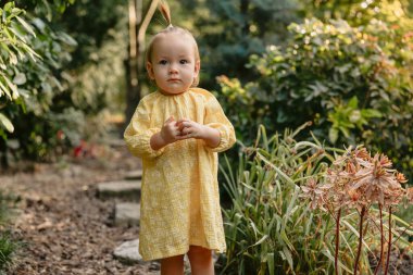 Şirin bir çocuk portresi. Sarı elbiseli küçük kız yaz bahçesinde.