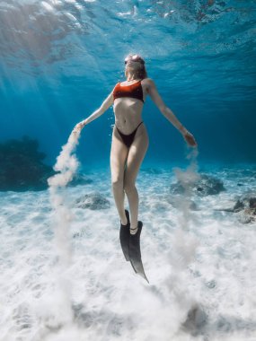 Freediver suyun altında yüzer ve kumla oynar. Tropikal mavi okyanusta çekici bir kadınla serbest dalış.