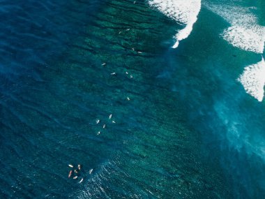 Açık mavi okyanusta sörfçülerin ve sörf dalgalarının olduğu hava manzarası
