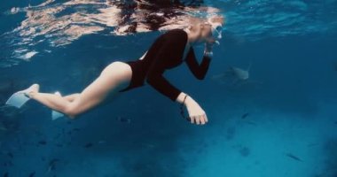 Dişi serbest dalgıç okyanusun yüzeyinde dinleniyor ve Maldivler 'deki tropik mavi denizde köpekbalıklarına bakıyor. Yüksek kalite 4k görüntü