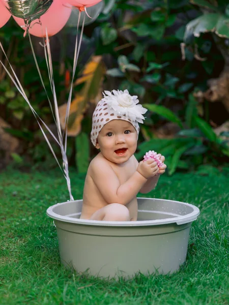 快乐的女婴和粉色的气球在宝宝浴池的室外夏季花园游泳 — 图库照片