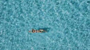 Şeffaf mavi okyanusta yüzen güzel bir kadının havadan aşağı görüntüsü. Yüksek kalite 4k görüntü