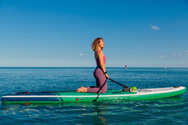 Ayakta duran bir kadın, güneşli bir yaz gününde sakin bir deniz. Okyanusta dinleniyor.