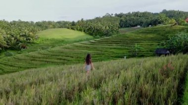 Bali 'de sabah güneşiyle teraslarda yürüyen bir kadın. Hava görünümü