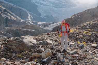 Sırt çantalı yürüyüşçü kadın kayalık dağlarda yürüyor..