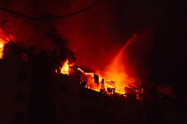 Yanan ev geceleri alevler içinde kalıyor. İtfaiyeciler suyla söndürüyorlar..