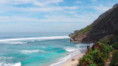 Kaya uçurumlu tropik plaj ve sörf dalgalı mavi okyanus. Yüksek kalite 4k görüntü