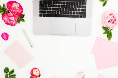 Bilgisayarlı ofis masası, pembe güller ve beyaz arka planda pembe günlük. Düz yatıyordu. Üst Manzara. Kopya alanı ile serbest konsept