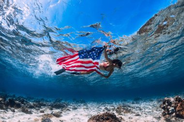 Serbest dalgıç ABD bayrağıyla tropikal denizde yüzüyor. Bağımsızlık Günü kavramı.