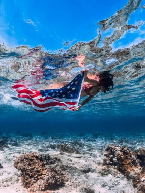 Tropik denizde Amerikan bayrağıyla şnorkelle yüzen bir kadın. Bağımsızlık Günü kavramı.