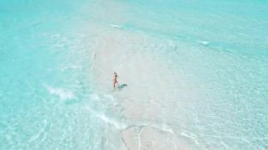 Mayo giymiş bir kadın turkuaz okyanusla kumsalda koşuyor. Tropik bölgelerde tatilde olan bir kızla hava manzarası. Yüksek kalite 4k görüntü