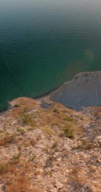 Dağ kıyıları, gün batımında sıcak tonlarla, dikey görüntülerle. Yüksek kalite 4k görüntü