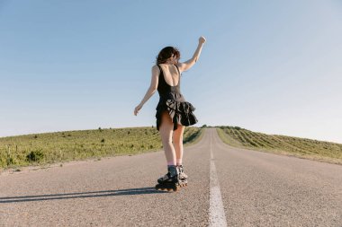 Güneşli bir günde paten süren genç bir kadın.