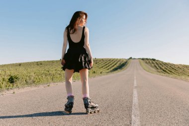 Güneşli bir günde dışarıda paten kayan güzel esmer bir genç kadın.