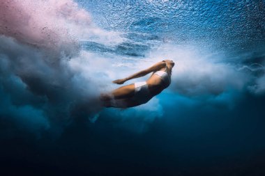 Sörfçü kız okyanus dalgalarıyla suya daldı. Sörf tahtası olmadan varil dalgalarının altına dalmak
