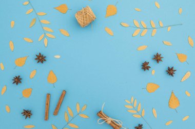 Sonbahar kompozisyonu mavi arka planda düşen yapraklardan oluşur. Düz yatış, üst görünüm.