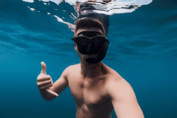 stock image Man free diver in mask shows Shaka hand. Swimming underwater in blue sea, selfie of handsome guy
