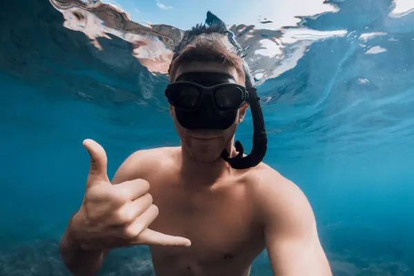 stock image Handsome man free diver in mask shows Shaka in blue ocean. Swimming underwater in blue sea, selfie of sporty guy