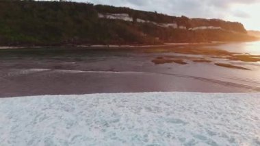 Alçak gelgit ve gündoğumu tonlarında okyanusla kaplı Bali kıyıları. İHA görüntüsü. Yüksek kalite 4k görüntü