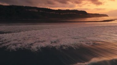 Alçak gelgit ve gündoğumu tonlarında okyanusla kaplı Bali kıyıları. İHA görüntüsü. Yüksek kalite 4k görüntü
