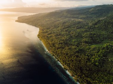 Endonezya 'daki tropik adalarda dağlarla ve gün doğumuyla birlikte cennet kıyı şeridi manzarası. Seyahat hedefi kavramı.