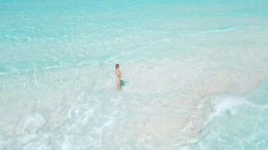 Kumsalda mayo giymiş turkuaz okyanuslu bir kadın. Tropik bölgelerde tatilde olan bir kızla hava manzarası. Yüksek kalite 4k görüntü