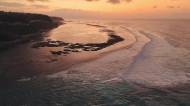 Alçak gelgit ve gündoğumu tonlarında okyanusla kaplı Bali kıyıları. İHA görüntüsü. Yüksek kalite 4k görüntü