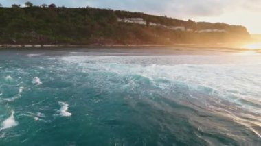 Alçak gelgit ve gündoğumu tonlarında okyanusla kaplı Bali kıyıları. İHA görüntüsü. Yüksek kalite 4k görüntü