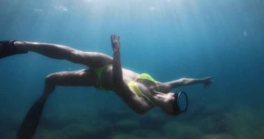 Bikini giymiş çekici bir kadın şeffaf tatlı su gölüne dalıyor, su altı manzaralı. Yüksek kalite 4k görüntü