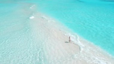 Kumsalda mayo giymiş turkuaz okyanuslu bir kadın. Tropik bölgelerde tatilde olan bir kızla hava manzarası. Yüksek kalite 4k görüntü