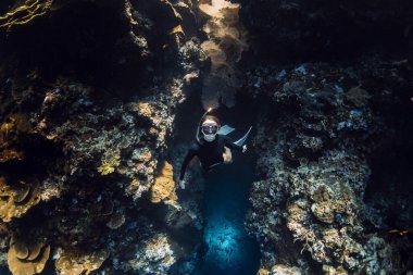 Serbest dalgıç kadın, Menjangan adasındaki tropikal denizdeki sualtı mağarasından çıkar. Bali 'de serbest dalış