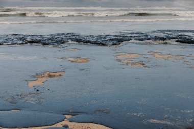 Deniz ve sahil yakıt yağıyla kirlenmiş. Plaj petrol sızıntısı etkisi, kirlilik, atık imhası.