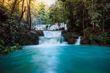 Cascade waterfalls with clear blue water and wooden bridge in Central Sulawesi clipart