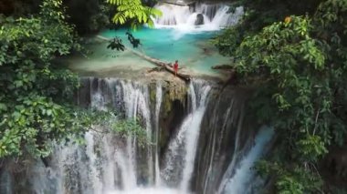 Şelalede, Sulawesi 'de berrak suyla gezen bir kadın. Luwuk 'ta manzara şelalesi, insansız hava aracı manzarası. Yüksek kalite 4k görüntü
