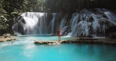 Şelalede, Sulawesi 'de berrak suyla gezen bir kadın. Luwuk 'ta manzara şelalesi. Yüksek kalite 4k görüntü