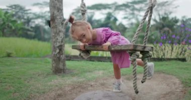 Çocuk tahta salıncaklarda oynuyor, çocukluğun tadını çıkarıyor. Yüksek kalite 4k görüntü