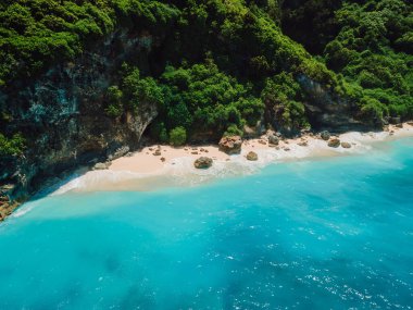 Kumlu tropik plaj, kayalar ve mavi okyanus manzaralı drone manzarası