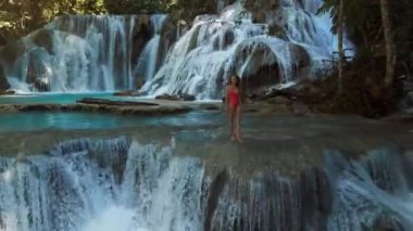 Şelalede, Sulawesi 'de berrak suyla gezen bir kadın. Luwuk 'ta manzara şelalesi. Yüksek kalite 4k görüntü